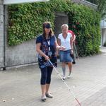 Eine Teilnehmerin mit Augenmaske benutzt einen Blindenstock zur Orientierung auf dem BBW-Gelände (vergrößerte Bildansicht wird geöffnet)