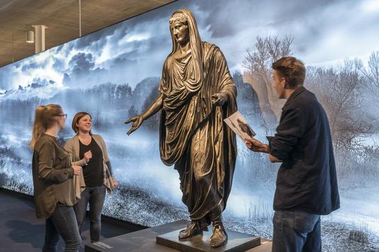 Schülerinnen und Schüler bestaunen die Bronzestatue des Tiberius. (vergrößerte Bildansicht wird geöffnet)