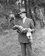 Zivilist aus Suttrop, vermutlich ein Arzt, mit der Leiche eines ermordeten Babys. Fototext: "German civilian holds body of Russian child he and other residents of Suttrop, Germany, were forced to exhume from its common grave. When U.S. Ninth Army troops occupied the town, informers led them to huge grave containing bodies of 57 Russian victims, including women and one baby, who had been forced to dig their own grave before they were shot by SS troops. American officers ordered German civilians to exhume the bodies, attempt identification with the aid of Russian Displaced Persones, and rebury them in individual graves with burial rites performed by a U.S. Army chaplain." / NARA, Washington