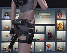 Cyberheldin Lara Croft blickt auf die Superman-Vitrine.