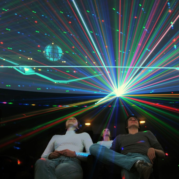 Menschen blicken nach oben auf eine bunte Laser-Show des Planetariums (vergrößerte Bildansicht wird geöffnet)
